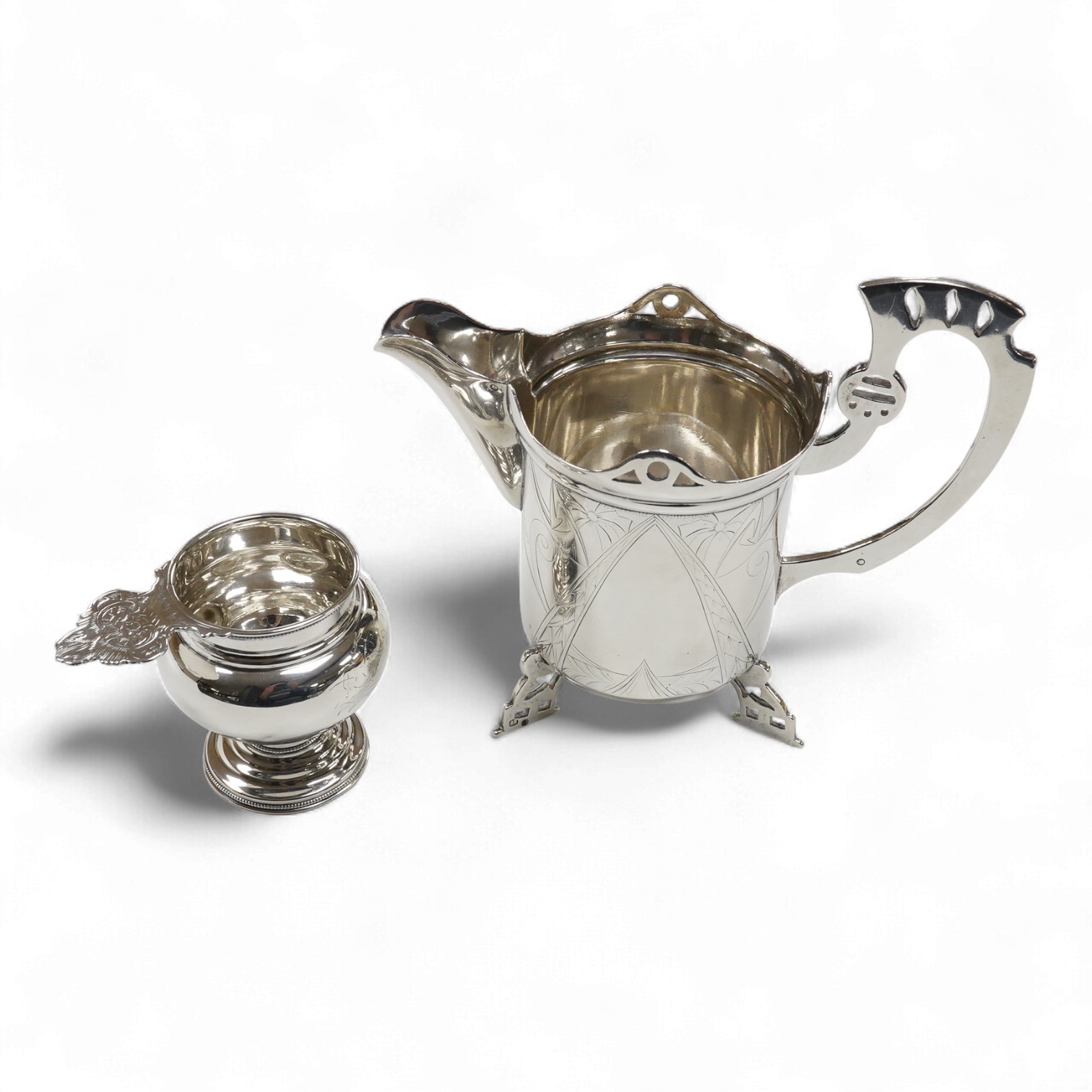 A late 19th/early 20th century Russian 84 zolotnik cream jug, with engraved decoration and angular feet and handle, master Andrei Ivanov, 1908-1917 kokoshnik mark, height 11.6cm, together with a similar single handled sm